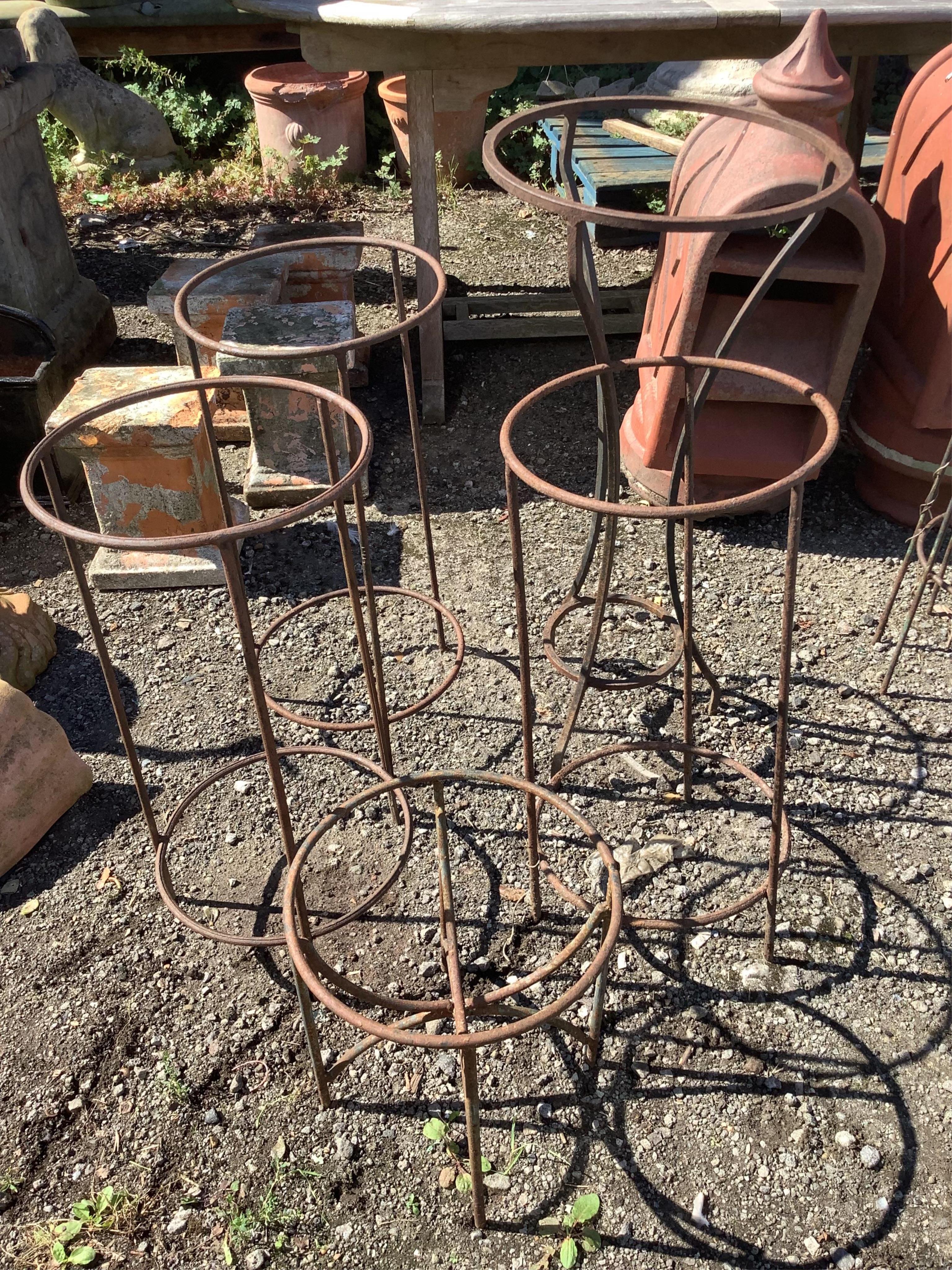 Four wrought iron garden growing frames and a circular pot stand, largest height 78cm. Condition - fair